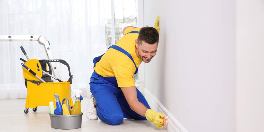Professional house cleaner scrubbing baseboards