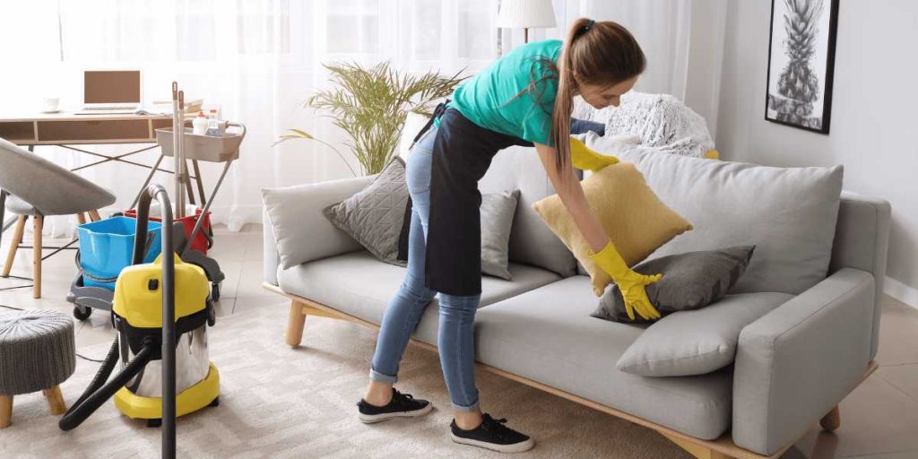 Professional housekeeper cleaning and vacuuming a living room